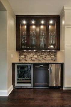 an empty refrigerator in a kitchen next to cabinets with wine glasses on them and lights above it