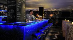 the bar is lit up with blue lights and chalk writing on the wall behind it