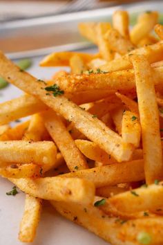 a pile of french fries sitting on top of a white plate