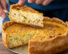 a person cutting into a quiche on top of a metal plate with a knife