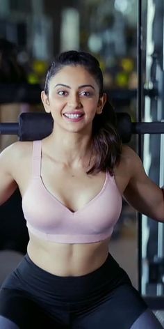 a woman in a pink bra top and black shorts squatting on a barbell