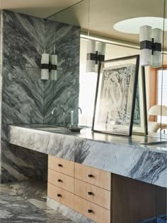 a marble counter top in a bathroom with two mirrors on the wall and one light hanging over it