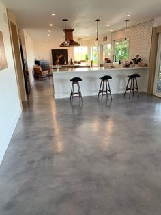 an empty kitchen and living room are seen in this image with stools on the floor