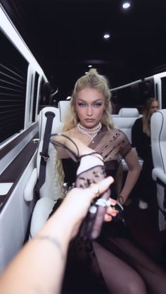 a woman is sitting in the back of a limo with her hand out to someone