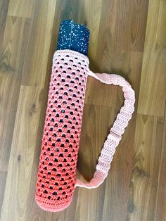 a crocheted bag sitting on top of a wooden floor next to a bottle