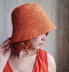 a woman wearing an orange crochet hat with no brimming on her head