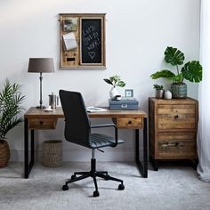 a desk with a chair, potted plants and a chalkboard on the wall