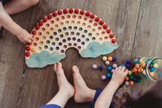 two children playing with colorful play dough on the floor in front of a child's hand