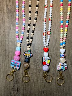 several different colored beads and key chains on a wooden surface