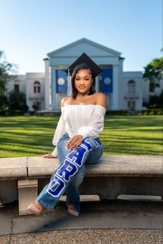 a woman sitting on a bench in front of a building wearing a cap and gown