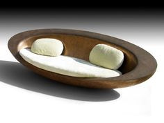 an oval shaped couch with two pillows on it's back and sides, sitting in front of a white background