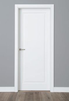 an empty room with a white door and wood flooring in front of a gray wall