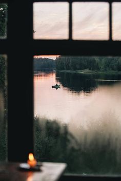 a candle is lit in front of a window with a view of the water and trees