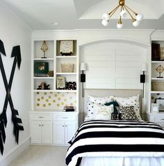 a bedroom with white walls and black and gold decor on the bed, along with bookshelves