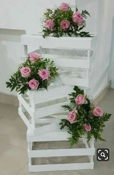 three white planters with pink roses in them on top of each other next to a wall