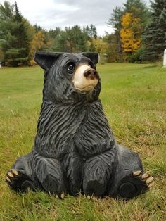 a black bear statue sitting in the grass