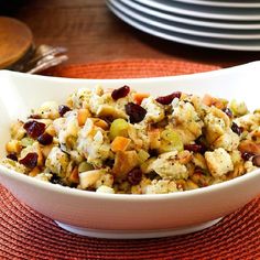 a white bowl filled with food sitting on top of a red place mat next to plates