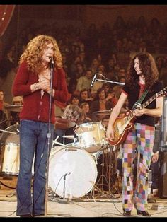 two women on stage with guitars and microphones in front of an audience at a concert