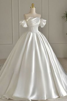 a white wedding dress on a mannequin in front of a wall and potted plant