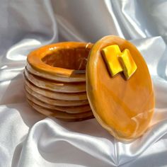 a stack of wooden plates with cheese slices on them sitting on a white cloth covered tablecloth