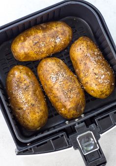 four baked potatoes sitting in an air fryer