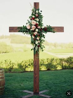 a cross with flowers on it in the grass