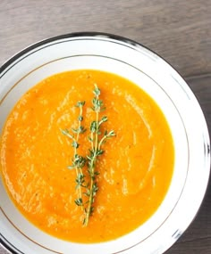 a white bowl filled with carrot soup on top of a wooden table