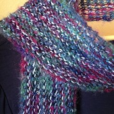 a woman is wearing a multicolored knitted scarf on top of a mannequin