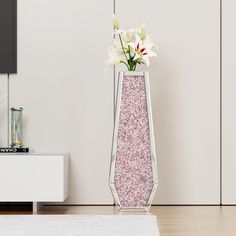 there is a vase with flowers in it on the floor next to a tv stand