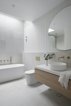 a white bathroom with a tub, sink and mirror in the corner next to it