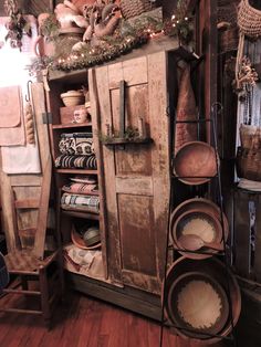 an old wooden cabinet with pots and pans on it in a room filled with other items