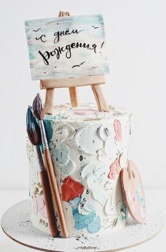 there is a cake with an easel and paintbrush on it