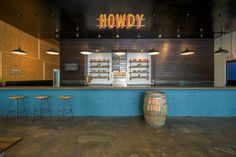 an empty bar with stools in front of it and a neon sign above the bar