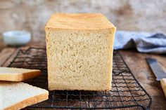 a loaf of bread sitting on top of a cooling rack next to slices of bread