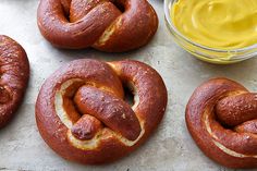 several pretzels on a baking sheet with mustard in the bowl next to them