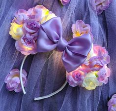 a purple headband with flowers on it and a bow at the top is laying on a tulle