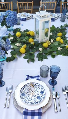 the table is set with blue and white plates, silverware, and lemons