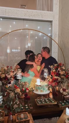 a group of people hugging each other in front of a cake