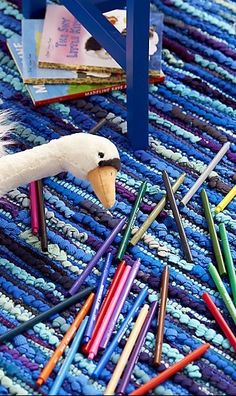 a stuffed swan is on the floor surrounded by crayons