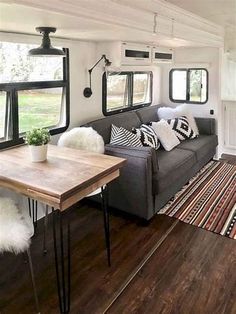 a living room filled with furniture next to a wooden table and white rug on top of a hard wood floor