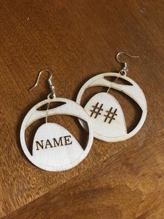 two wooden earrings with hash on them sitting on top of a wood table next to a pair of silver earwires