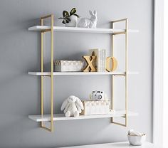 two white shelves with gold trim on the top and bottom, against a gray wall