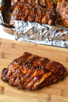 some meat is sitting on a cutting board next to tin foil and another food item