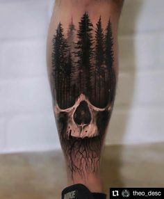 a man's leg with a skull and trees on it