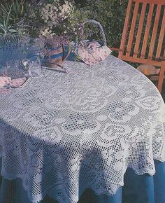 the table is covered with white crocheted doily and has flowers on it