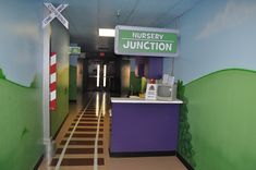 the entrance to nursery junction is painted with green and purple paint on the walls, along with a sign that says nursery junction