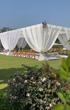 an outdoor wedding setup with white drapes and chairs