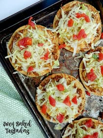 small pizzas with cheese and tomatoes are on a baking sheet