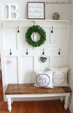 a bench with a wreath on the wall above it and some hooks to hang them