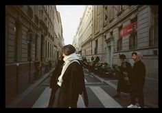 two people walking down the street in front of some buildings